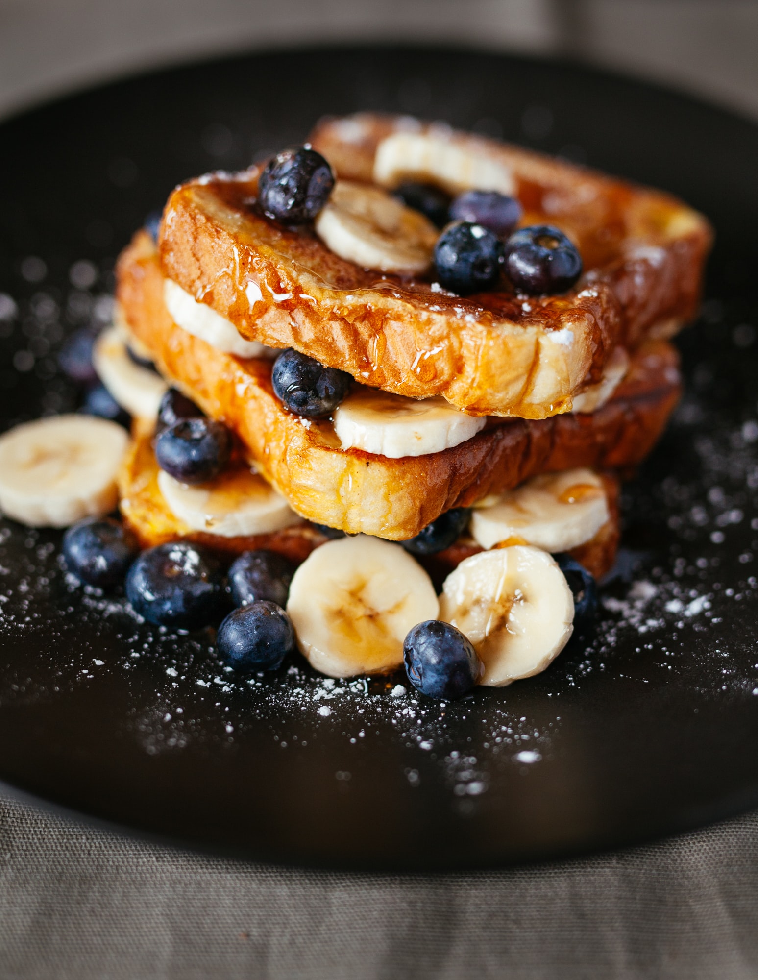 A plate of french toast with blueberry and banana