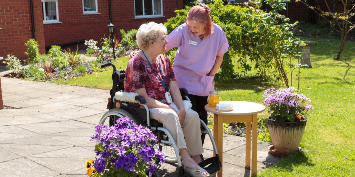 Borough Care staff member taking care of a care home resident who is sat in a wheelchair.